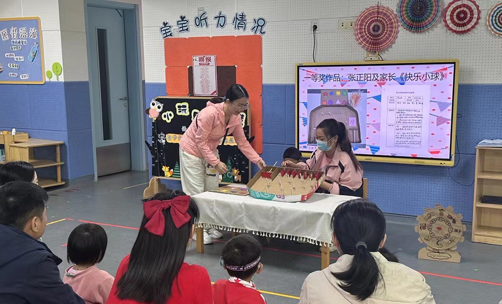 图为家长携幼儿展示自制玩教具的玩法.jpg